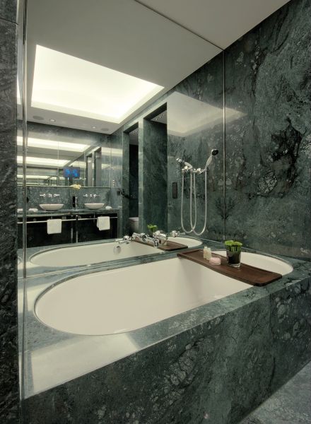Badewanne in der Massino Suite mit großem Spiegel und Steinoptik