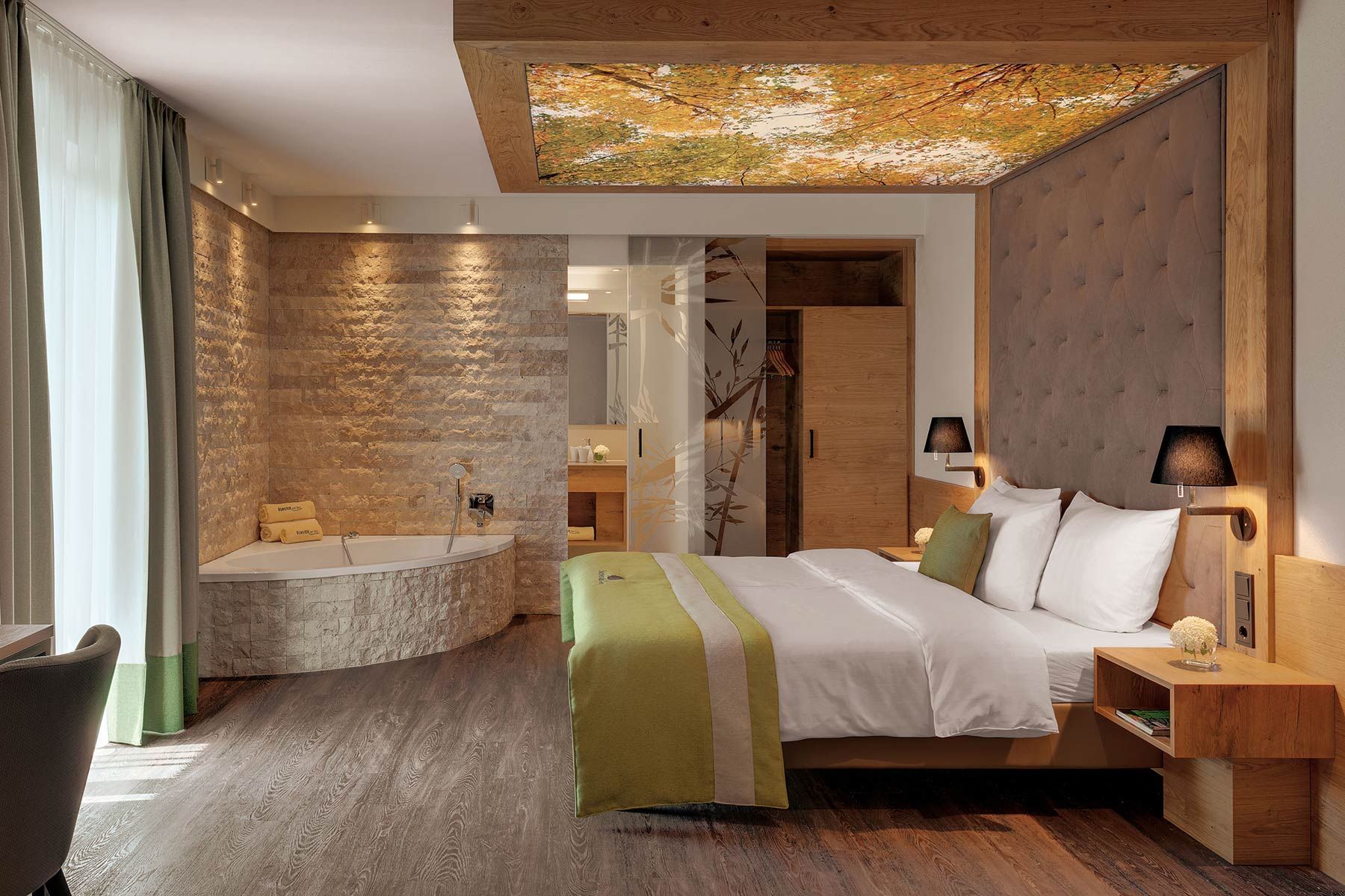 Hotelzimmer mit inkludierter Badewanne und ansprechender Deckengestaltung