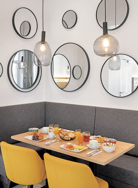 Frühstücksraum in gelb-grauer Farbgebung und mit dekorativen Wandspiegeln