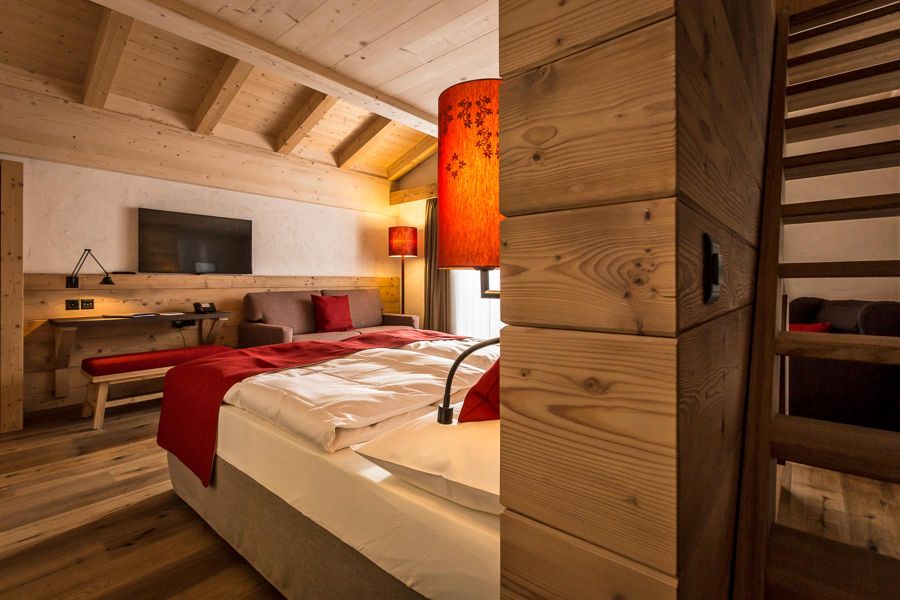 Warmes Hotelzimmer mit Holzparkett am Boden und Fichtenholz an der Decke.