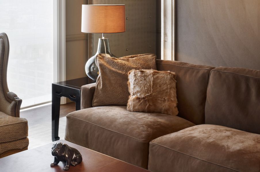 Braune samte Couch mit Fellkissen, Beistelltisch und einer Tischleuchte 