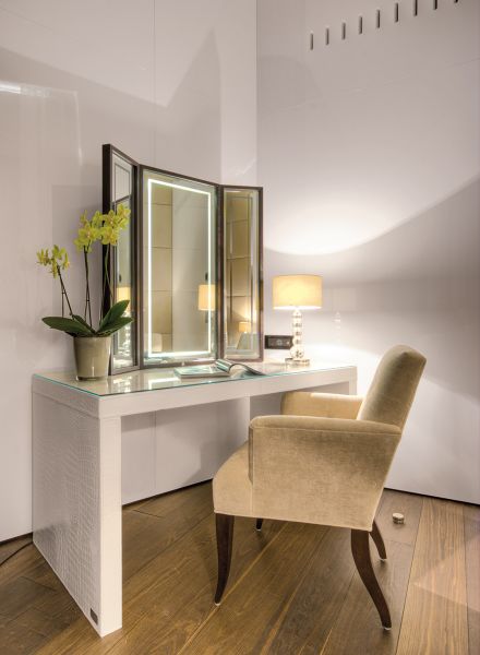 Dreigeteilter Spiegel auf weißem Tisch mit Glasplatte sowie Sessel, verschiedenste Lichtszenarien und einer Orchidee