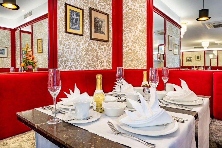 Restaurantbereich mit gedecktem Tisch, roten Polstermöbeln und edler Tapete