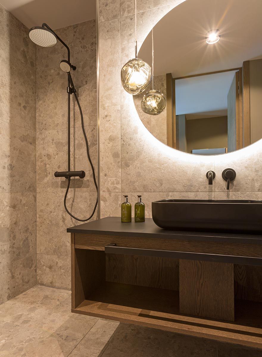 hotel bathroom with stone tiles and wooden washbasin