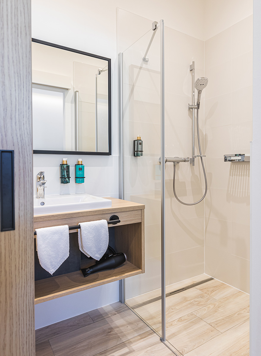 Badezimmer mit Waschtisch und Dusche in warmen Farbtönen