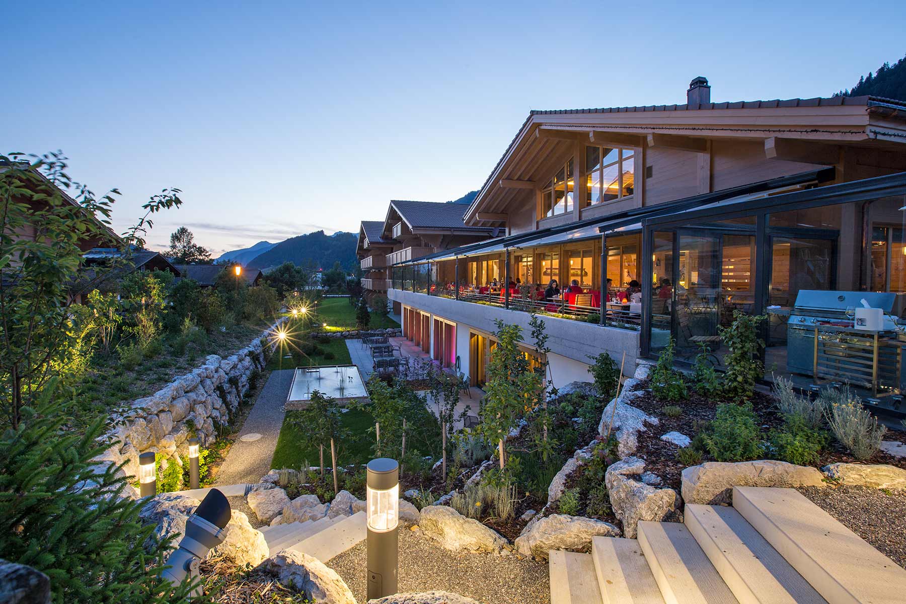 Aussenbereich mit schönem Hotelgarten durch modernes Lichtkonzept und Steinmauern.