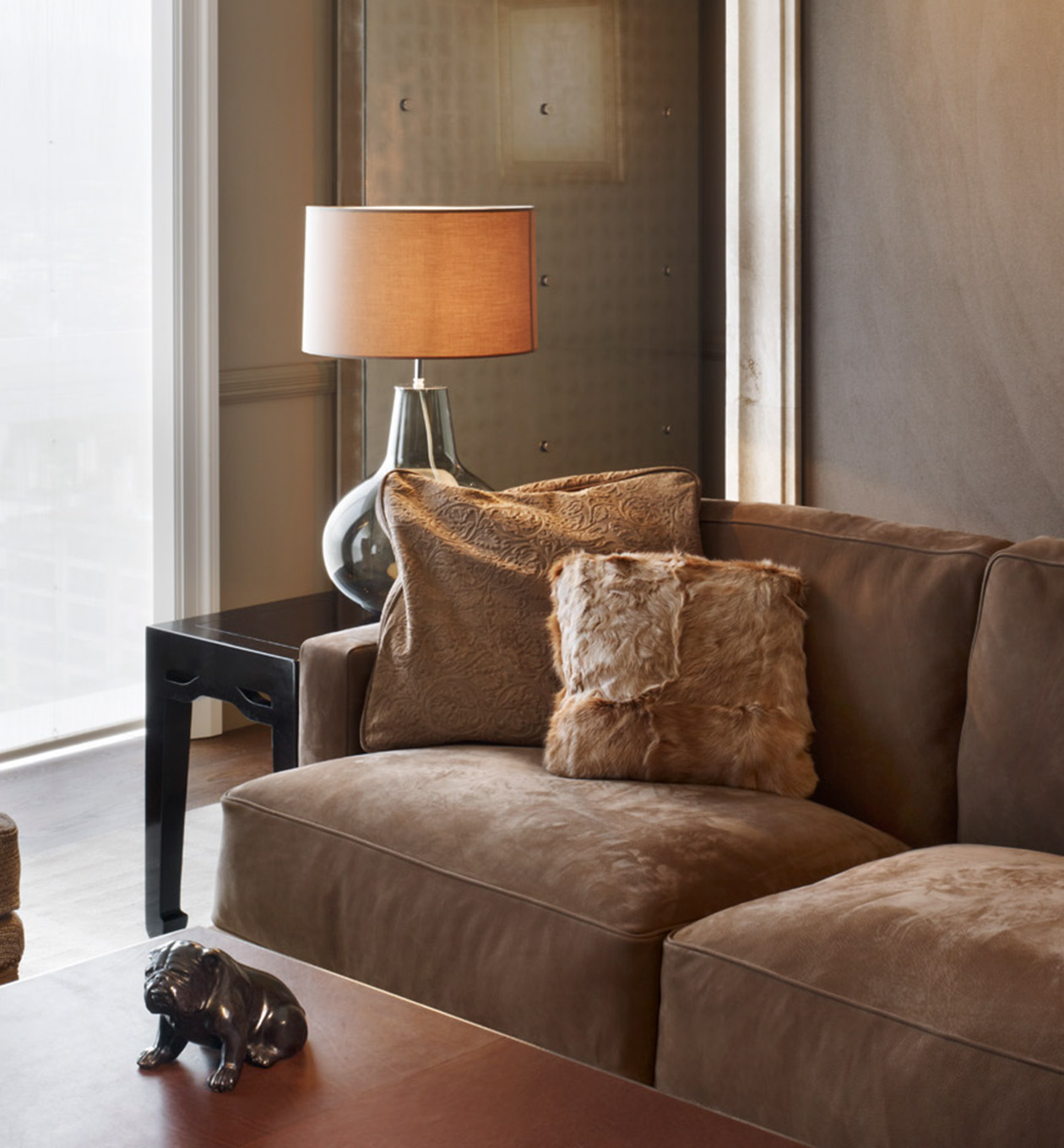 Braune samte Couch mit Fellkissen, Beistelltisch und einer Tischleuchte