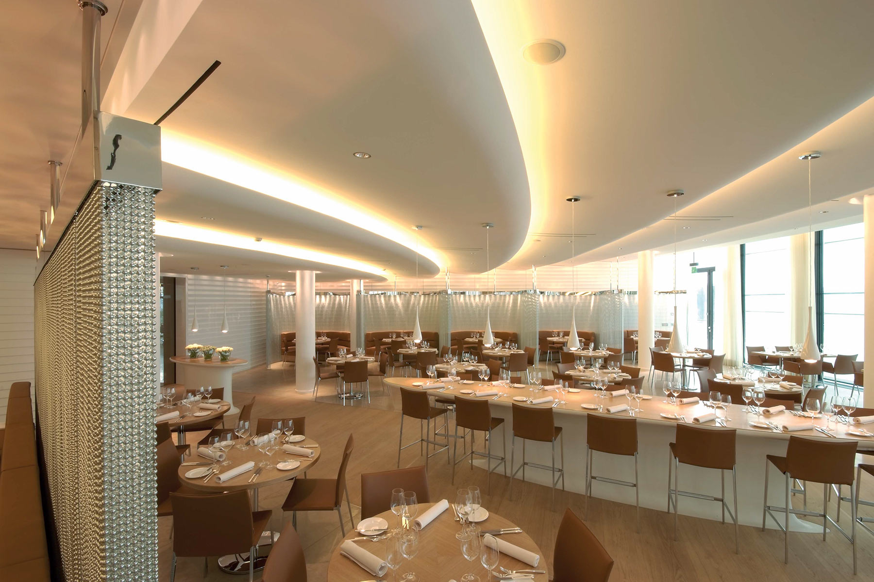 Restaurant im The Grand Dolder in Z&uuml;rich mit einem langen Tisch und Barhockern