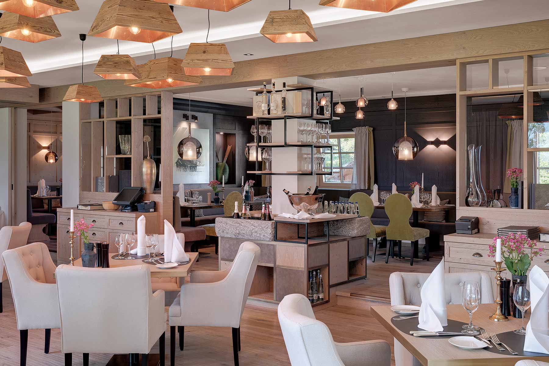 Restaurantbereich des Alpenhof mit dekorativen Lampen und gr&uuml;nen und beigen St&uuml;hlen 