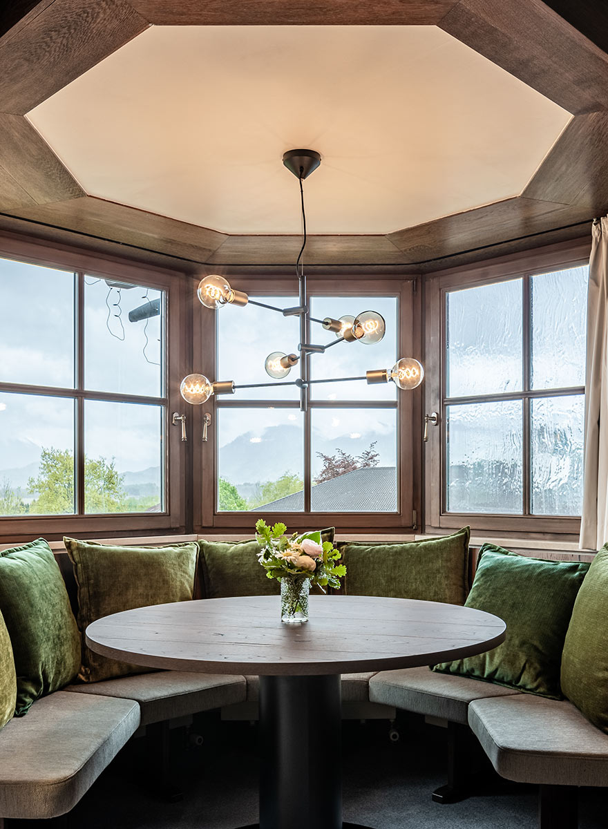 abgerundete Eckbank aus Holz mit Aussicht und dekorativer Lampe