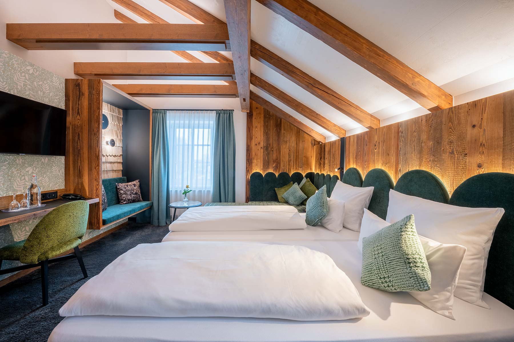 Hotelzimmer mit Altholz-Wandverkleidung und gr&uuml;nen Bettkopfteilen