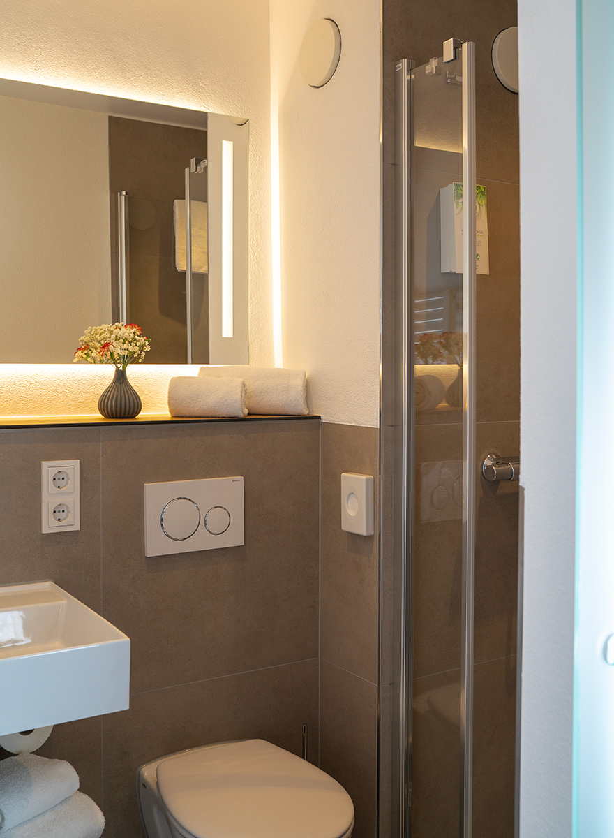 Helles und kompaktes Badezimmer halbwegs gefliest mit WC und Dusche