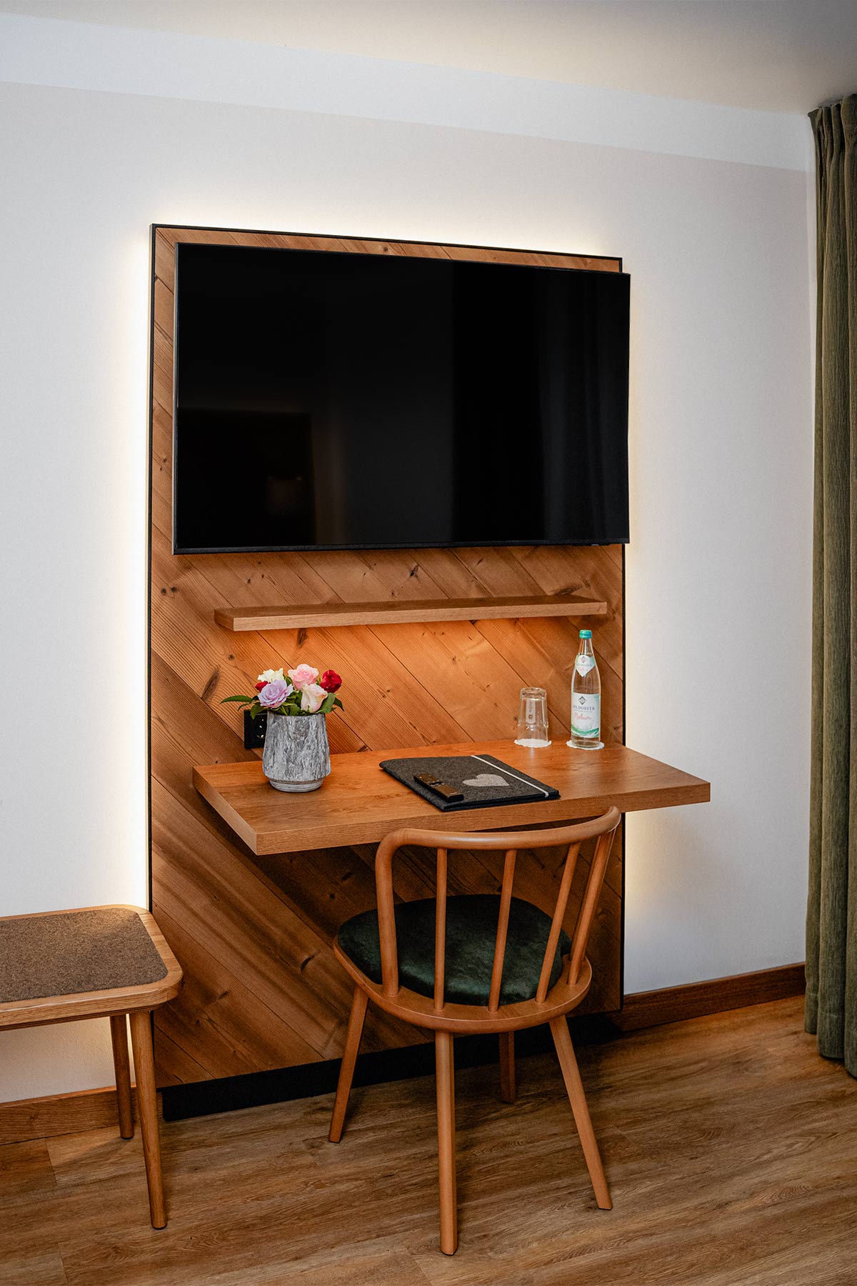 Zimmer mit stilvollen Blumen, TV, einem Stuhl und rustikaler Wanddekoration aus Holz.
