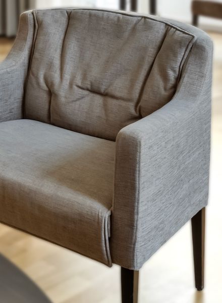 Nahaufnahme eines komfortablen Sessels im Hotel Rathauspark Wien von Appia mit weicher Rückenpolsterung und geradlinigen Armlehnen in dezentem Grau