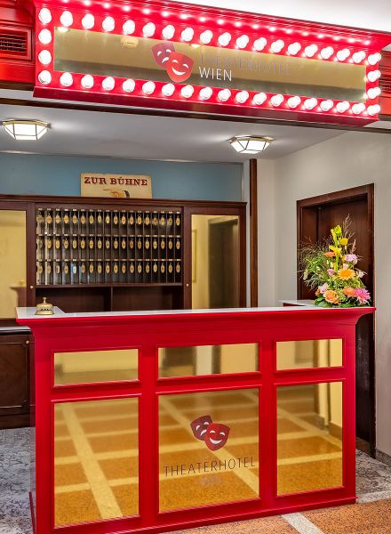 Rezeptionsbereich des Theaterhotels in goldener und roter Farbgebung