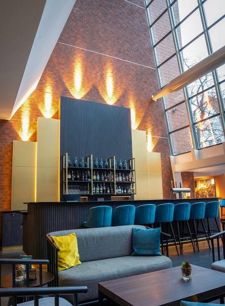 Kombination aus gemütlicher Lounge und stilvoller Bar mit blauem Samt und Goldakzenten