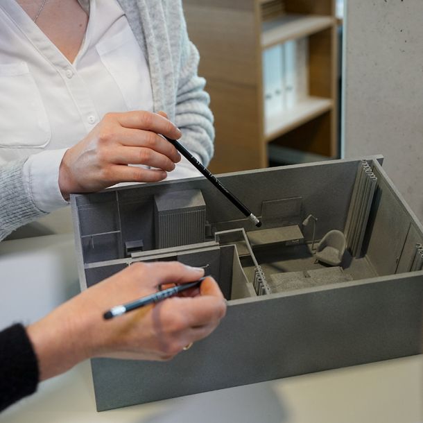 Innovatives Hotelzimmer mit 3D Modell präsentiert von den Innenarchitektinnen symbolisiert durch Bleistift und integriertem Firmenlogo APPIA