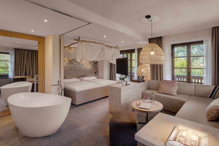 Zimmer mit freistehender Badewanne und Doppelbett in natürlichen Farben 