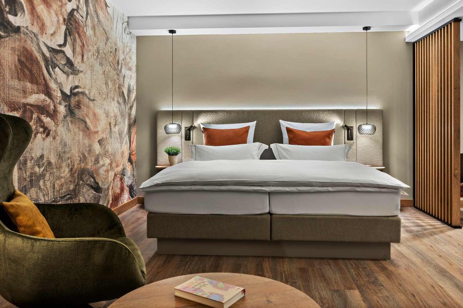 Prinzess-Zimmer Churfürstenhof Bad Birnbach zeigt großes Doppelbett dekorative florale Wandtapete und bequemen Sessel