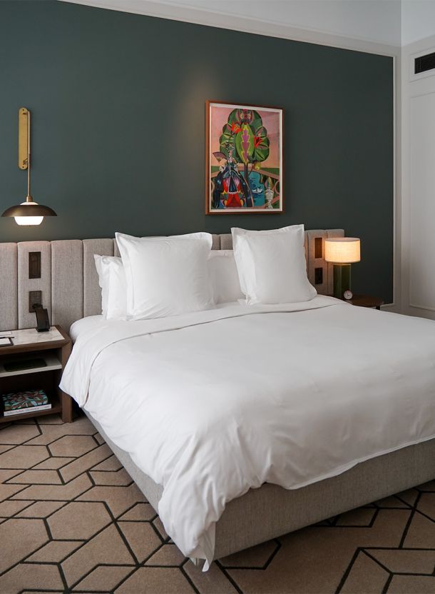 Schlafbereich im Rosewood Hotelzimmer München mit zentralem Doppelbett geometrischem Teppich Wandkunst und warmer Atmosphäre