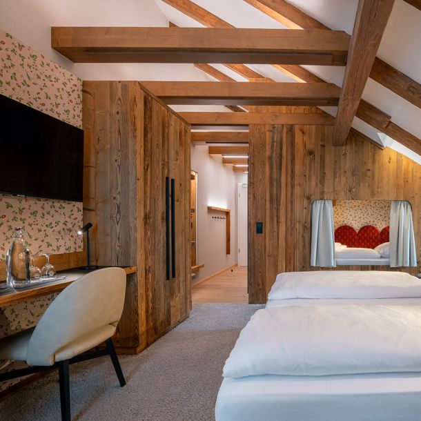 Gemütliches Gästezimmer in der Pension Schäfflerwirt Aschheim mit Blumentapete Holzdetails und stimmungsvollem Warmlicht