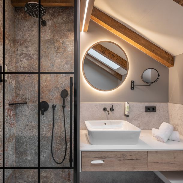 Modernes Badezimmer im Hotelzimmer des Gasthaus Schäfflerwirt Aschheim mit Dusche, WC und hochwertigen Fliesen im Landhausstil
