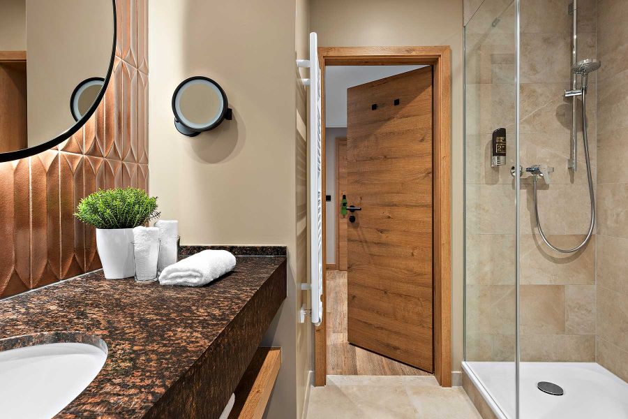 Dunkle Arbeitsplatte und helles Holzregal bestimmen Design im Badezimmer Churfürstenhof Bad Birnbach