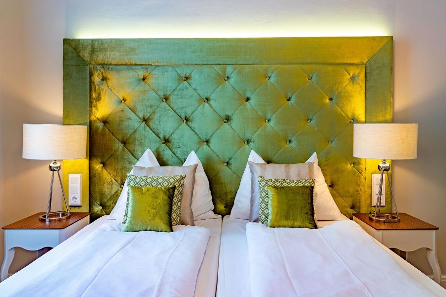 Doppelbett mit einer Samt-R&uuml;ckwand in gr&uuml;n und dazu passenden Dekokissen