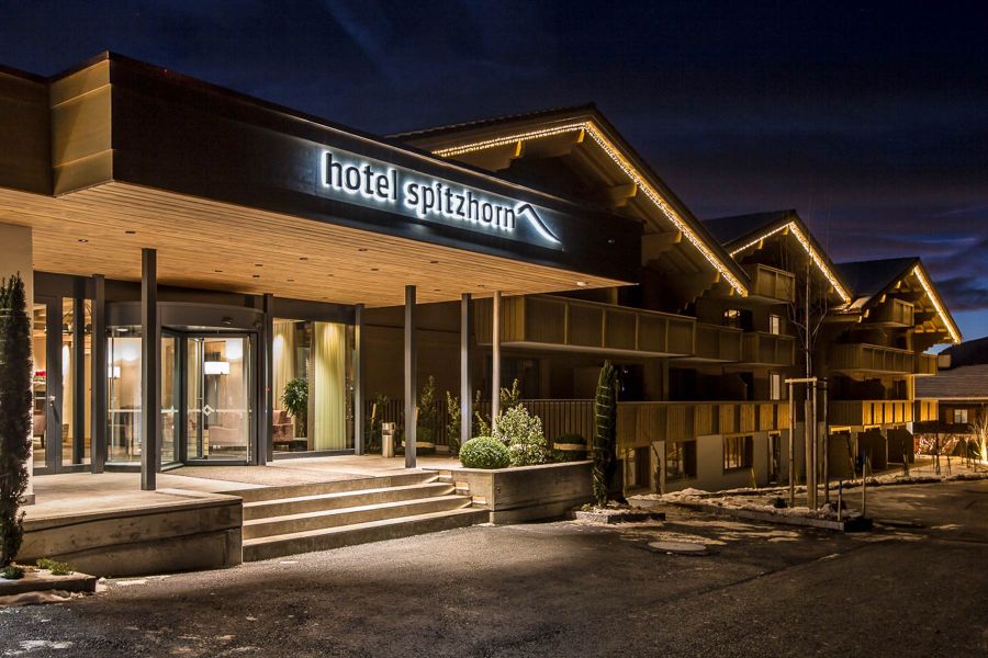 Hotelgebäude von Aussen im modernen Look mit Holzfassade und beleuchteter Hotelbeschilderung