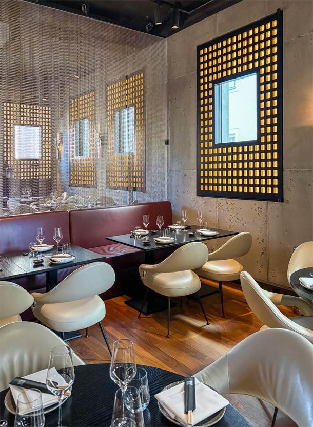 Restaurantbereich im Do & Co Hotel München mit gedeckten Tischen gepolsterten Loungesesseln Lederbank und halbtransparentem Vorhang als Raumteiler