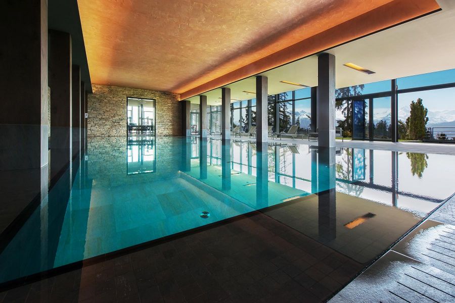 Gro&szlig;fl&auml;chiges Schwimmbecken im Wellness-Bereich mit Blick auf die Berglandschaft
