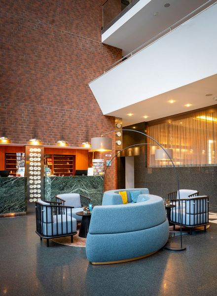 Lounge-Sitzecke mit pastellblauen Sesseln, dunklen Metallrahmen und warmem Lichtkonzept