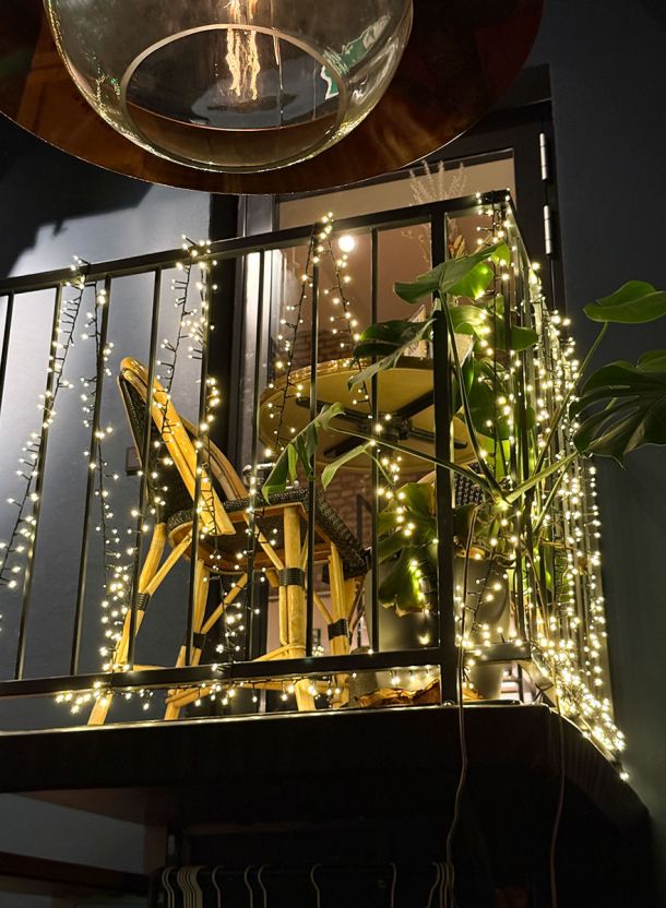 Abendstimmung im Restaurant mit dekorativer Beleuchtung an Metallstruktur Tischgruppe auf erhöhter Ebene und warm ausgeleuchtetem Innenraum