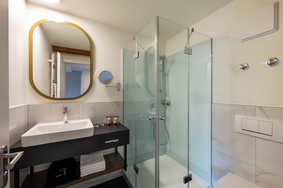 renoviertes Hotelbad mit Dusche und Waschtisch