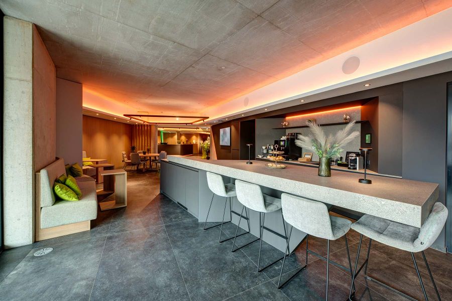 In Lounge integrierte Küche mit großer Steinplatte und Barhockern in grau