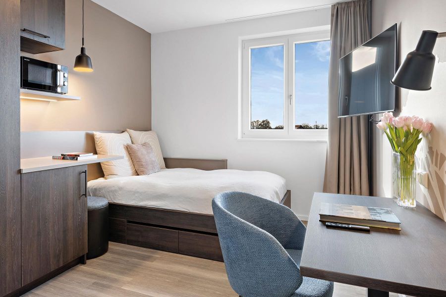 Hotelzimmer im Personalwohnhaus mit Bett, Tisch und Kochnische