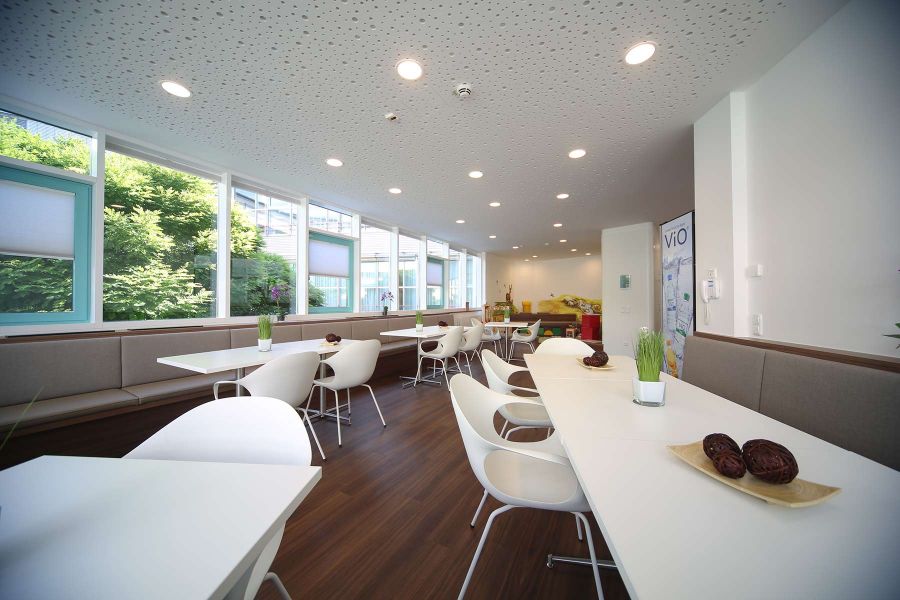 Aufenthaltsraum mit weißen Tischen und Stühlen