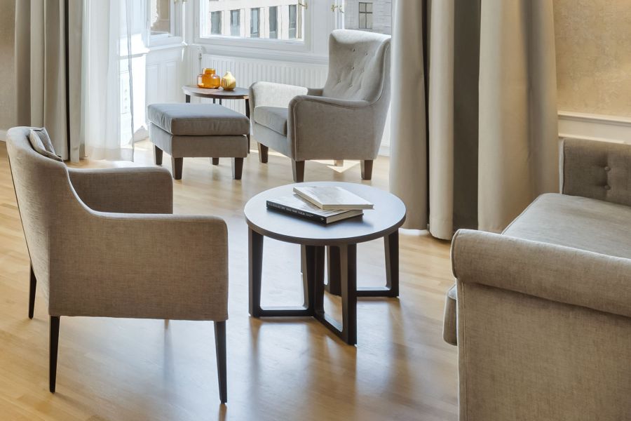 Blick auf eine komfortable Leseecke mit Fokus auf das Zusammenspiel von natürlichem Licht und weichen Textiloberflächen der Einrichtung