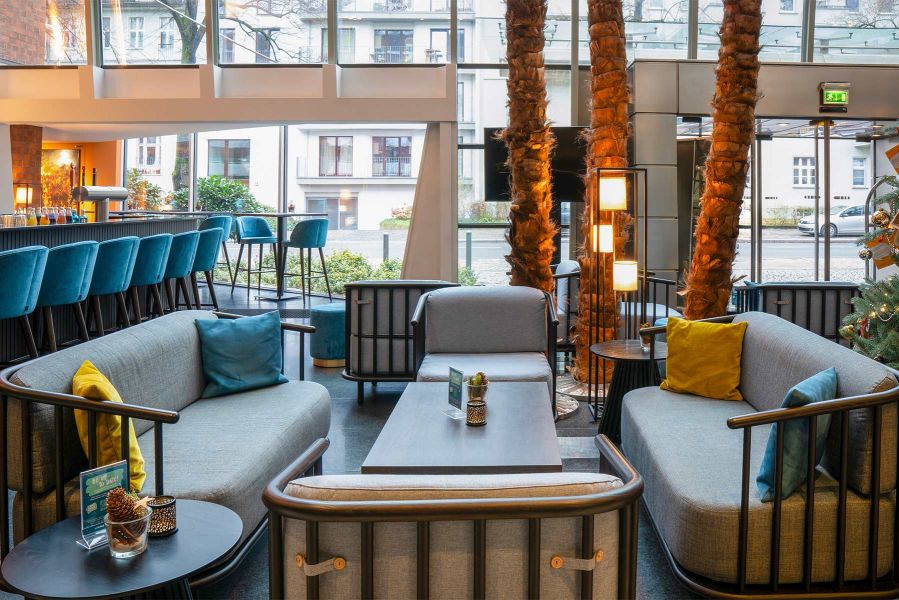 Gro&szlig;z&uuml;gige Lounge mit Palmen, Designm&ouml;beln in hellen T&ouml;nen und urbanem Ambiente