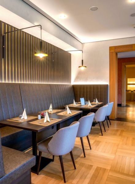 Essbereich mit gepolsterten St&uuml;hlen, Wandverkleidung aus Holz und indirekter Lichtleiste