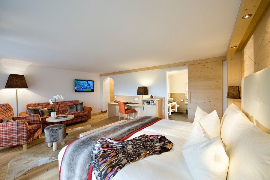 großzügiges Hotelzimmer mit Couch und Schreibtisch im Golfhotel