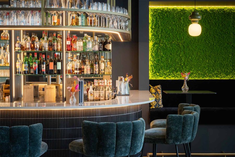 Barzone mit halbrundem Tresen dunkler Fliesenoptik und beleuchtetem Regal im Hintergrund