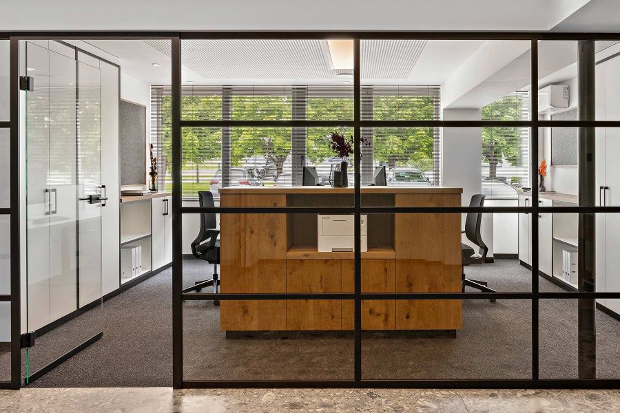 moderne B&uuml;roeinrichtung mit Glastrennwand, Sideboard und h&ouml;henverstellbaren Schreibtischen