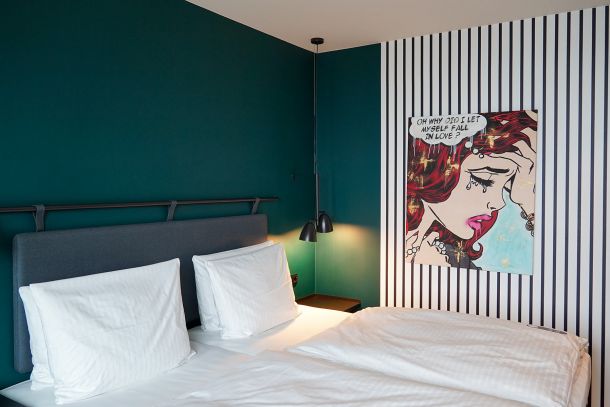 Zimmerdetail im Dorint Business Campus Garching mit Doppelbett gepolstertem Bettkopfteil akustisch wirksamer Wandfläche und dunkelgrüner Farbgestaltung von Appia